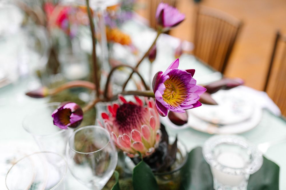 Close-up of vibrant pink and purple flowers in a glass vase on an elegant table setting.