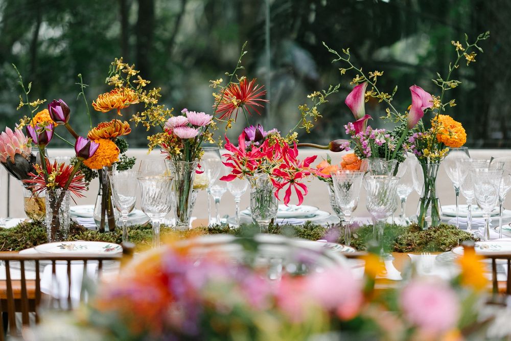 Colorful wildflower centerpieces in glass vases arranged along a rustic dining table.