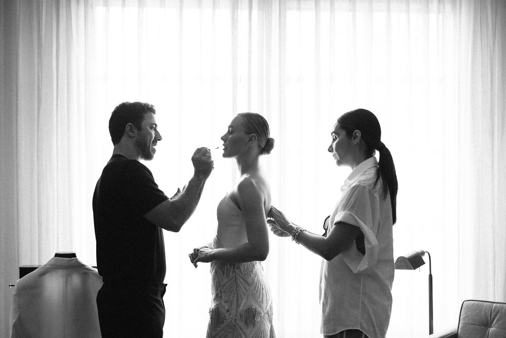 Black and white photo showing preparations in a bright room with backlit curtains.