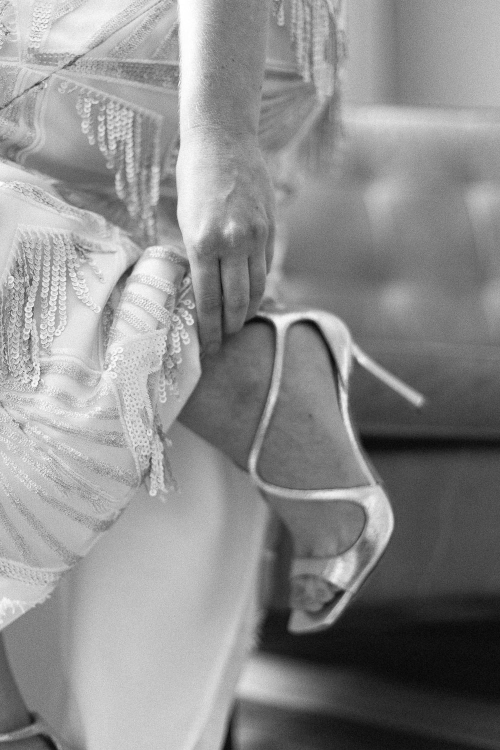Black and white detail shot of an elegant high heel shoe with lace dress fabric.