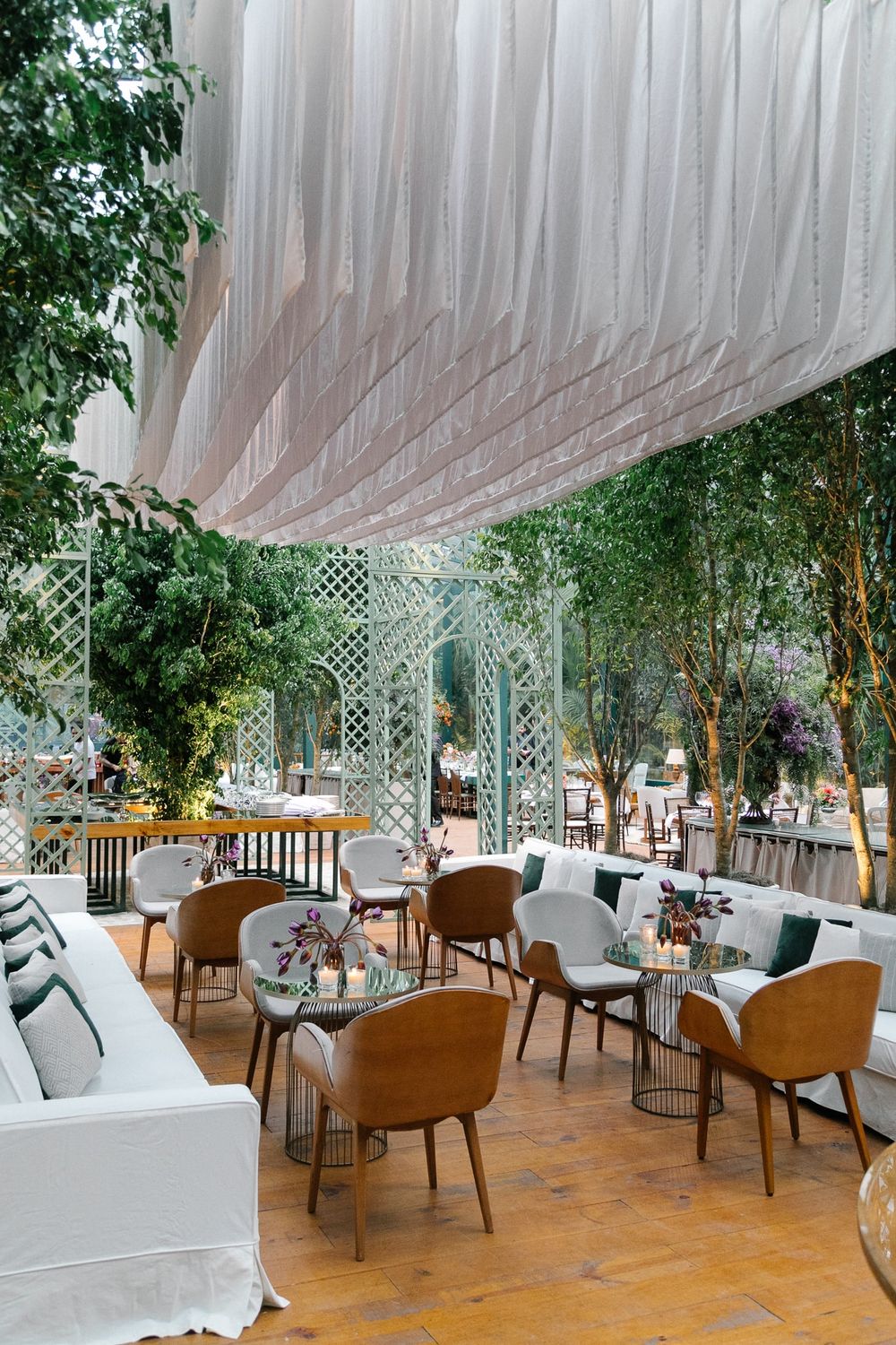 Elegant restaurant interior with draped white ceiling and green plants.