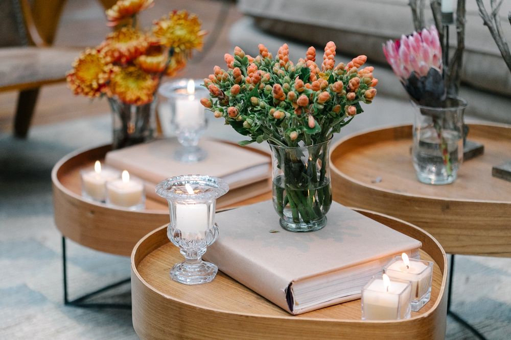 Coffee table setting with fresh flowers, candles, and books on round wooden trays.
