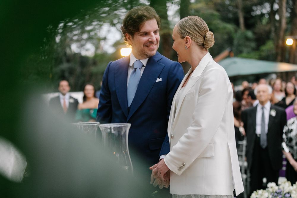 Intimate moment between newlyweds during outdoor garden ceremony with guests in background.