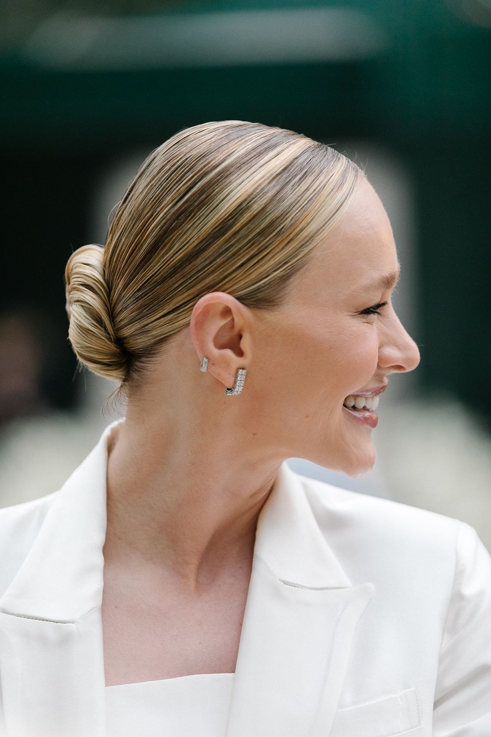 A side profile portrait showing a sleek updo hairstyle and white formal attire.