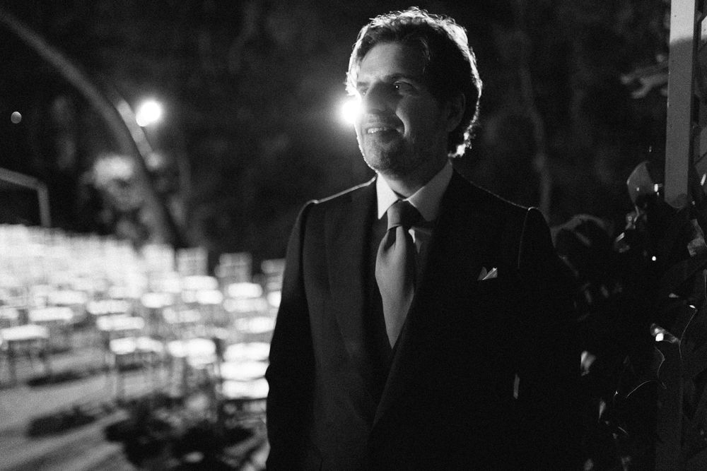 A dramatic black and white portrait of someone in formal attire at an outdoor evening event.