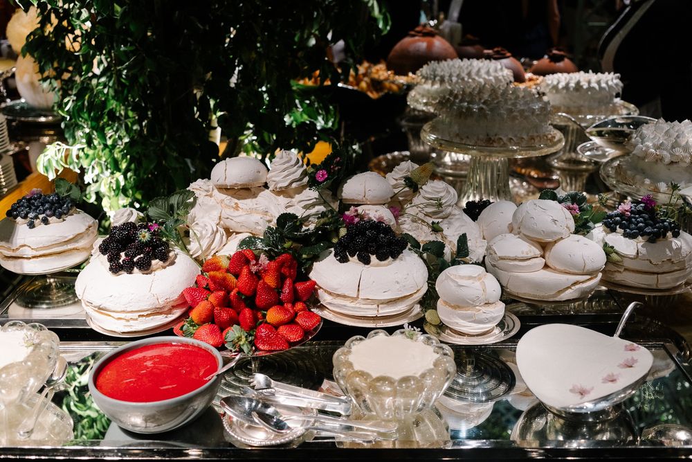 Elegant dessert table with white meringue cakes, fresh strawberries and crystal cake stands.