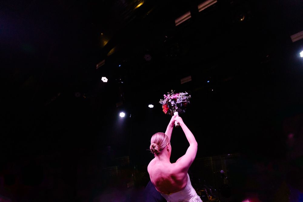 A performer raises a trophy triumphantly on a darkened stage with dramatic lighting.