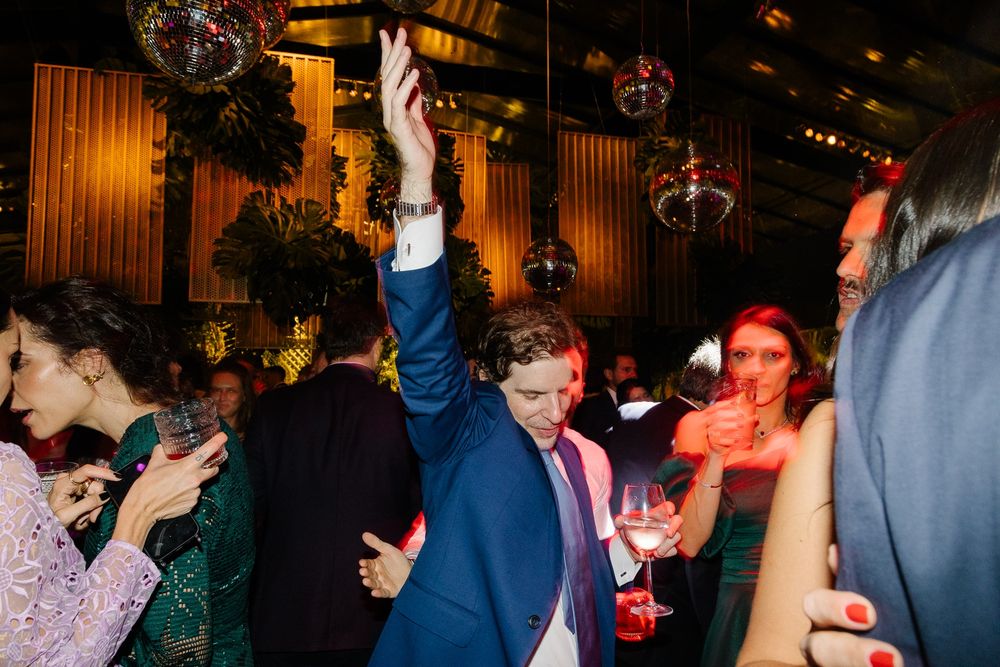 Guests dancing and celebrating with raised arms at a festive indoor reception.