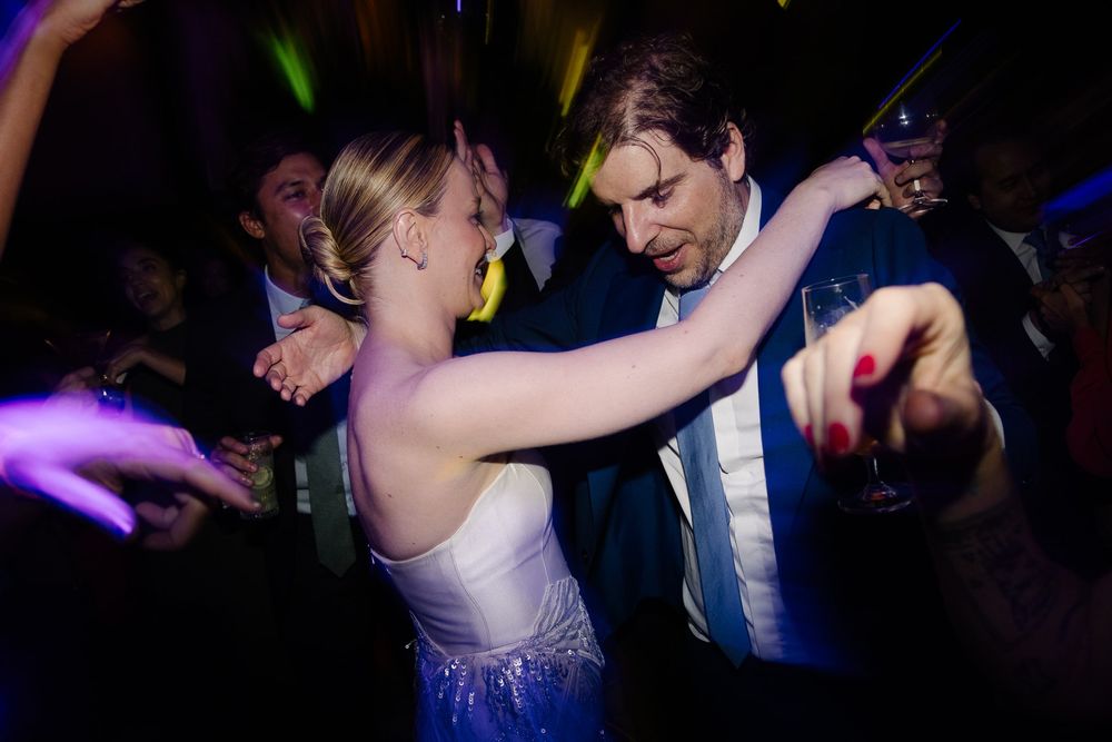A couple dances energetically on a dark dance floor illuminated by purple lighting.