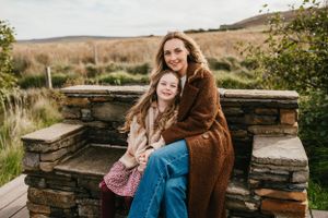 Two people share a joyful moment seated on rustic stone steps in an outdoor autumn setting.
