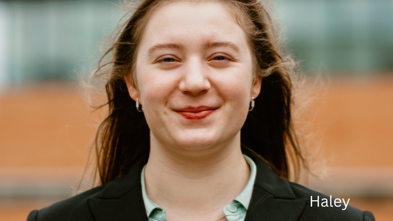 Professional headshot portrait against blurred urban background.