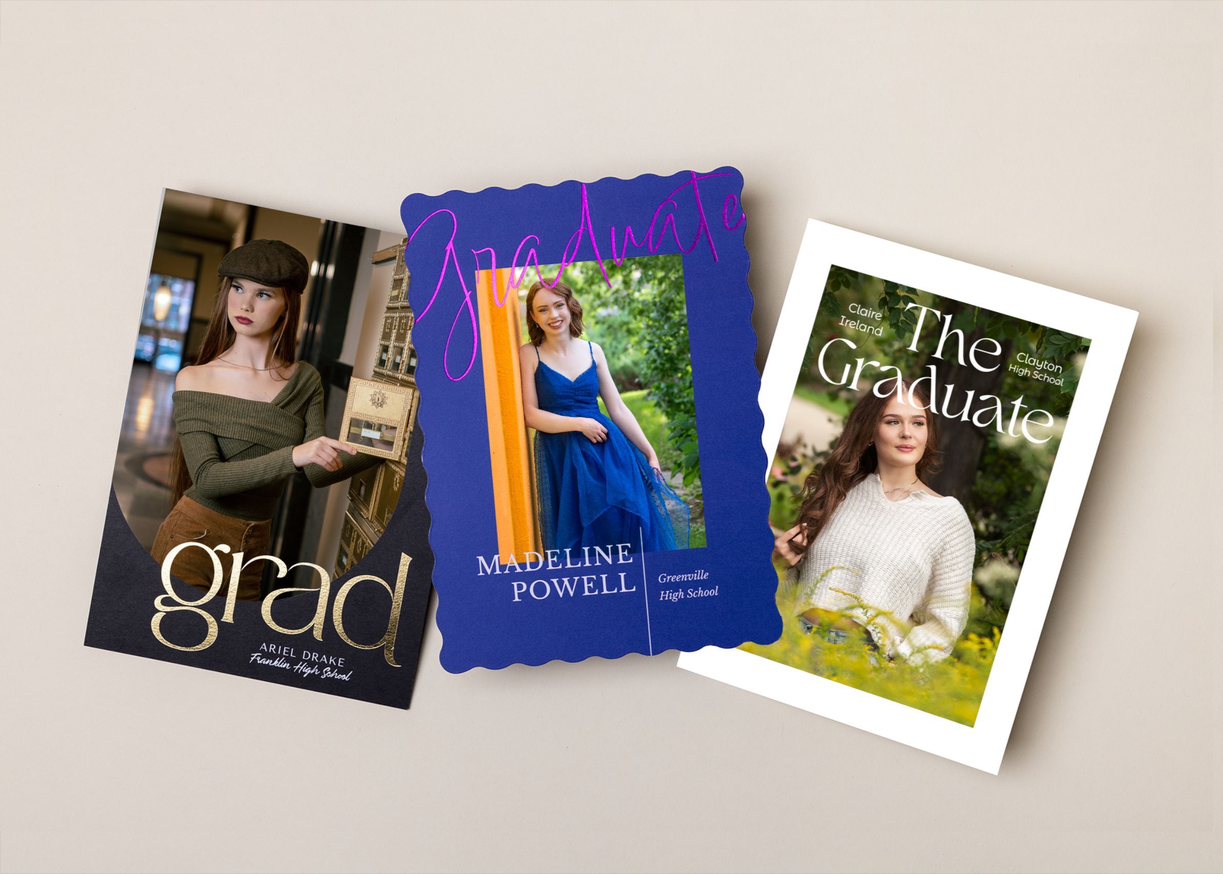 Three graduation announcement cards featuring portraits laid out on a light colored surface.