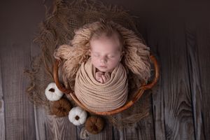 Artistic overhead photo series of a sleeping baby wrapped in beige fabric against a dark wooden background.