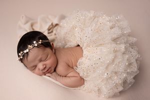 Delicate newborn photography portraits featuring soft pink and cream tones with sparkly tulle details.