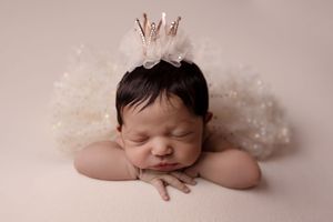 Series of artistic newborn portraits with white lace and sparkly details against a neutral backdrop.