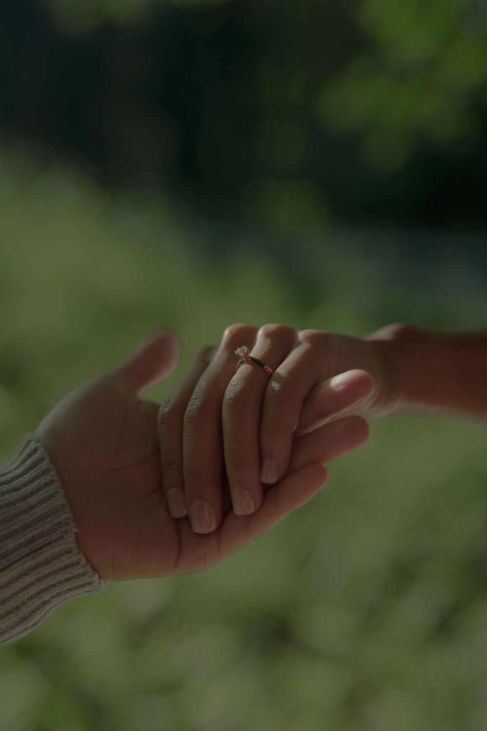 Close-up of two hands clasped together with a ring visible in natural lighting.