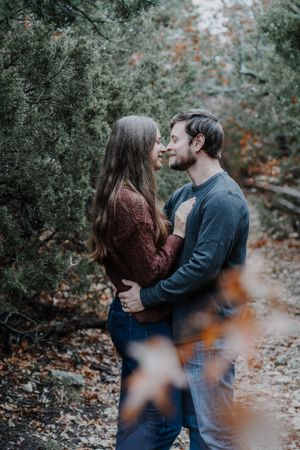 Intimate couple moment captured in moody forest setting with autumn colors.