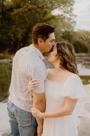A romantic couple shares an intimate moment in a natural outdoor setting.