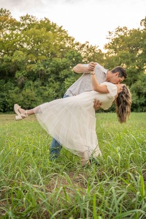 A playful dip pose captured in a grassy field during sunset.