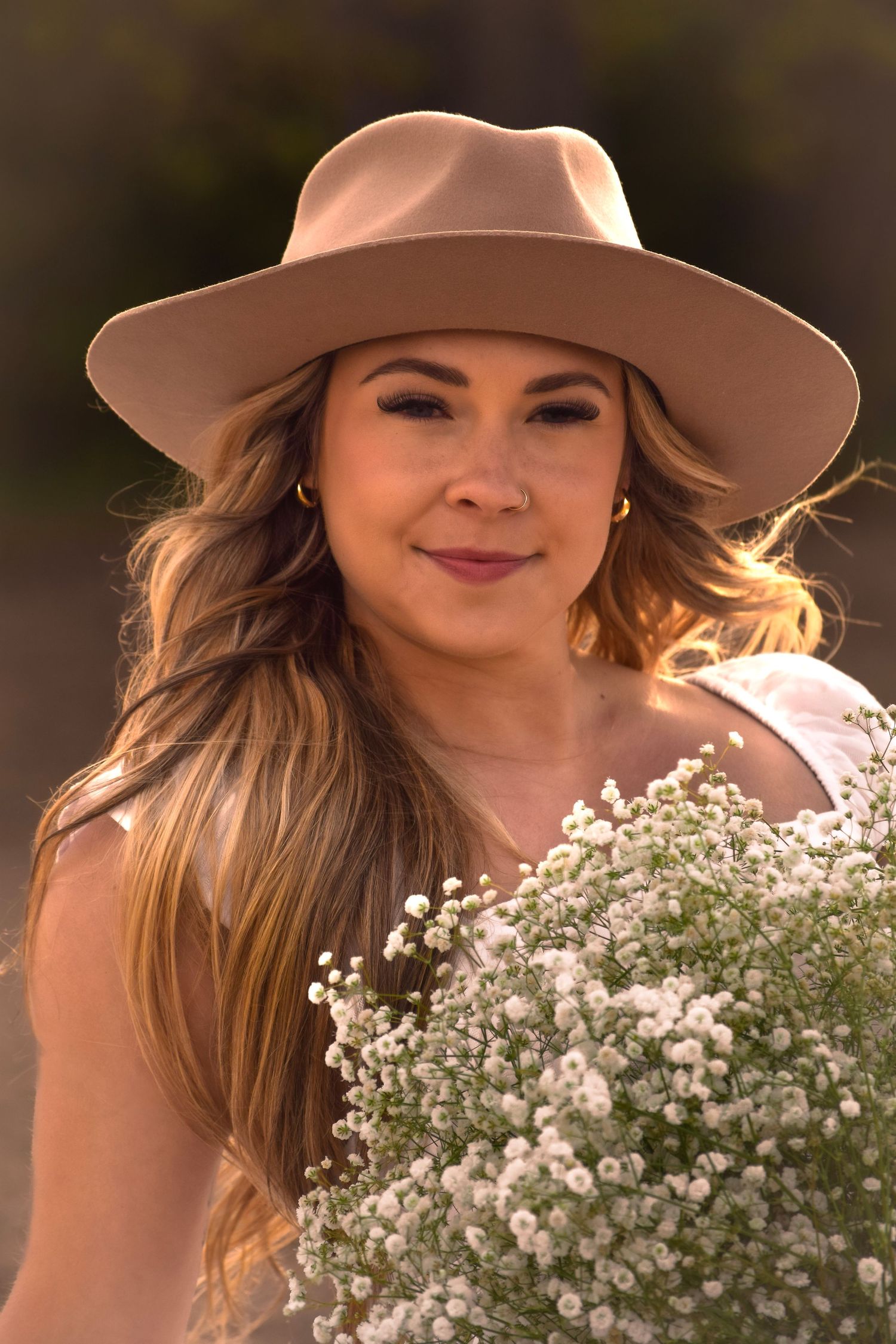 Portrait with white baby's breath flowers and tan hat in warm sunset lighting.