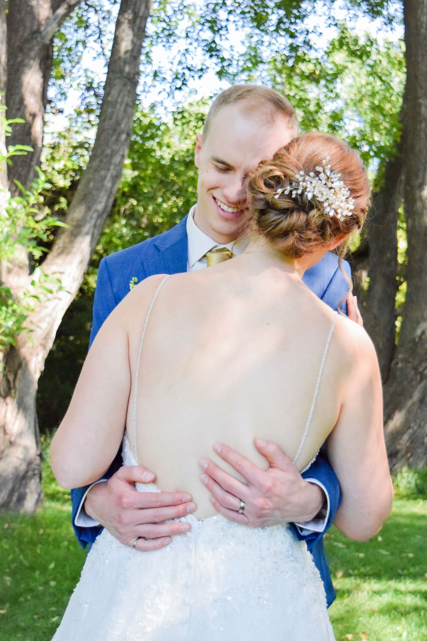 Couple embraces during intimate outdoor wedding photo session surrounded by trees.