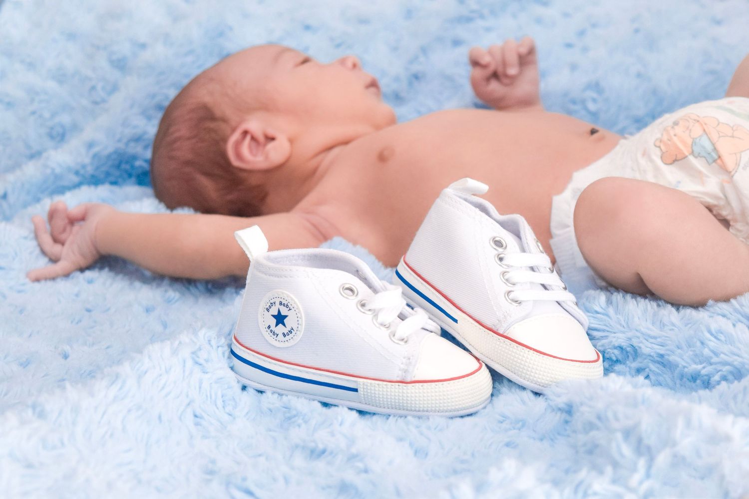 Small baby shoes placed on light blue textured background.