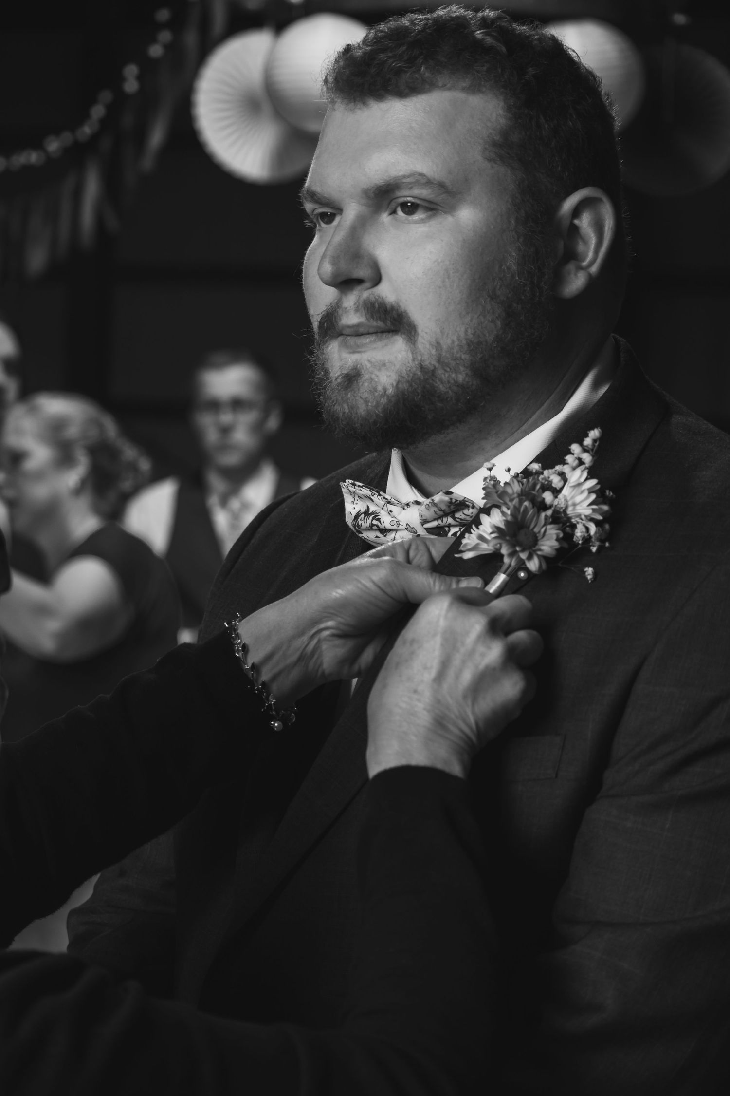 Black and white photo showing groom wearing bow ties and suits during a wedding ceremony.
