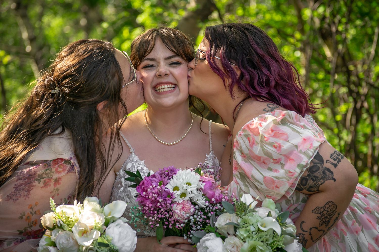 Bridesmaids in floral dresses hold colorful bouquets while posing together in a garden setting.