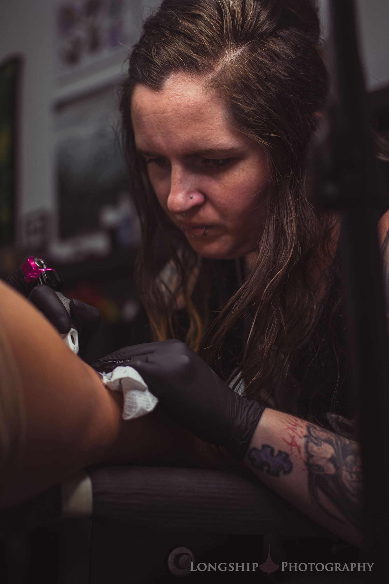 Tattoo artist working on a client in a dimly lit studio.