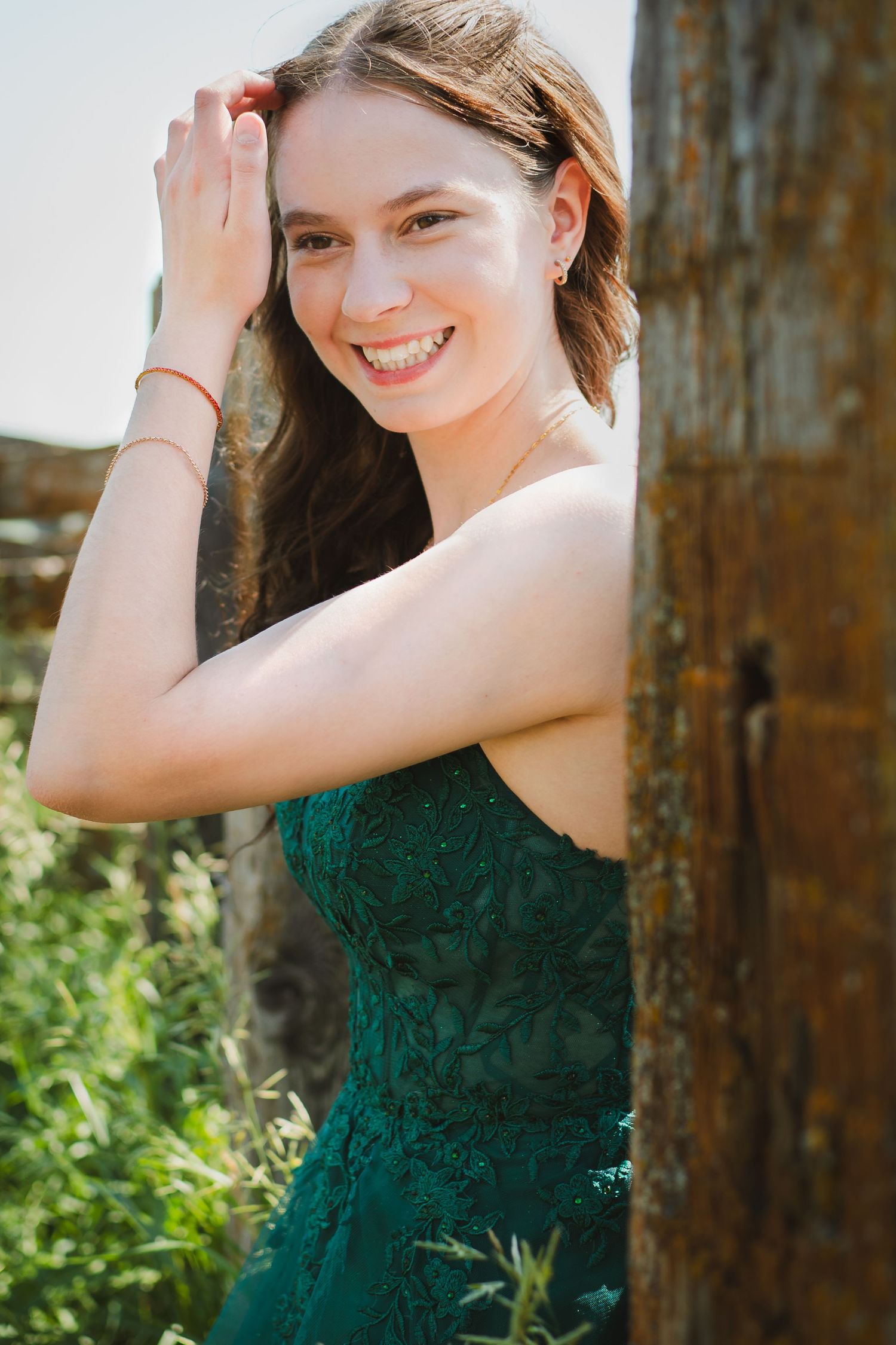 An elegant emerald lace gown shimmers against a rustic wooden backdrop in natural lighting.