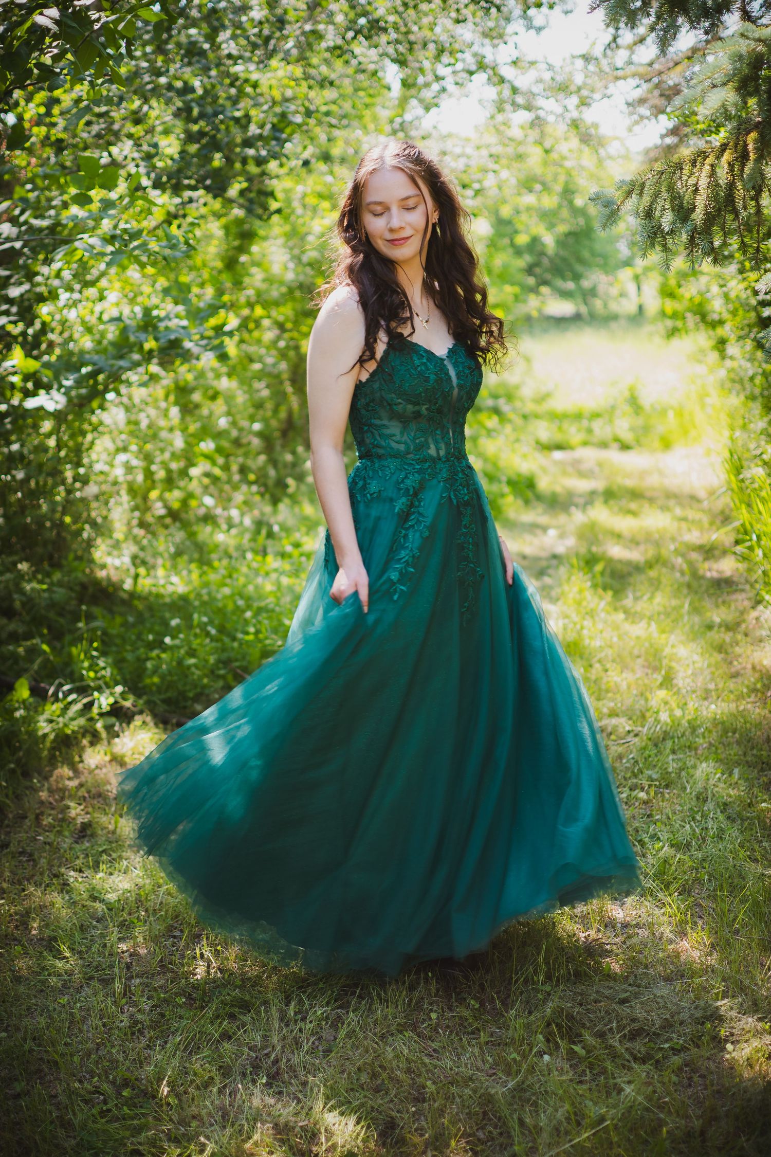 A stunning teal ballgown with tulle skirt flows beautifully in a lush garden setting.