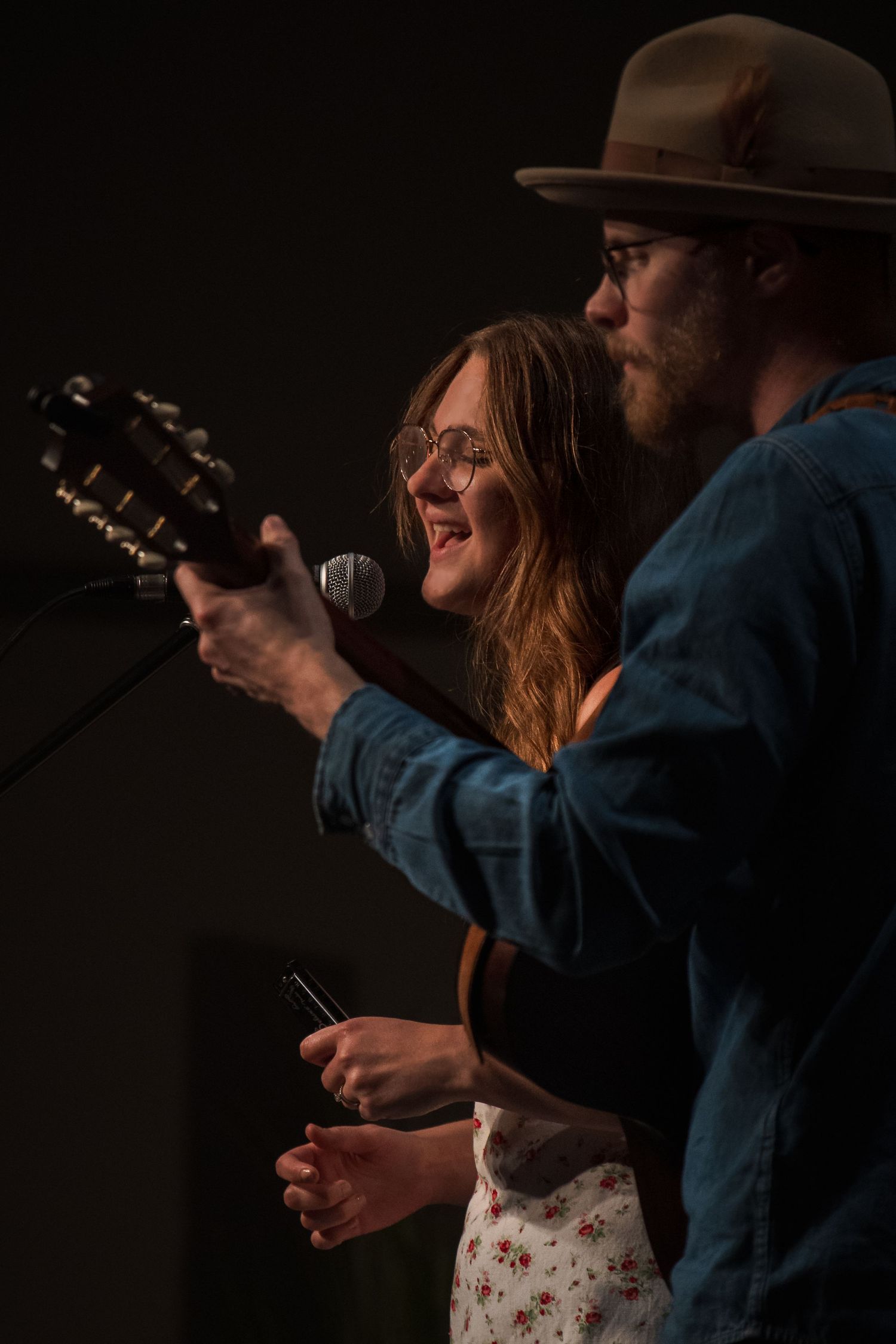 Musicians performing on stage in dim lighting with guitars.