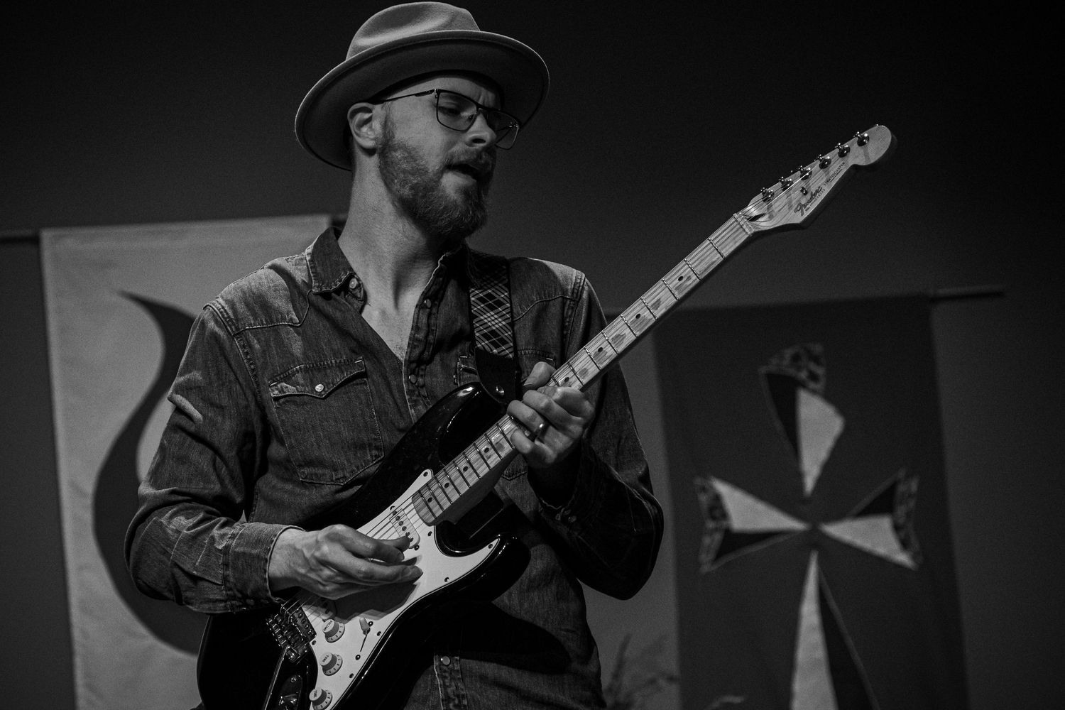 Guitar player performing on dark stage with dramatic lighting.