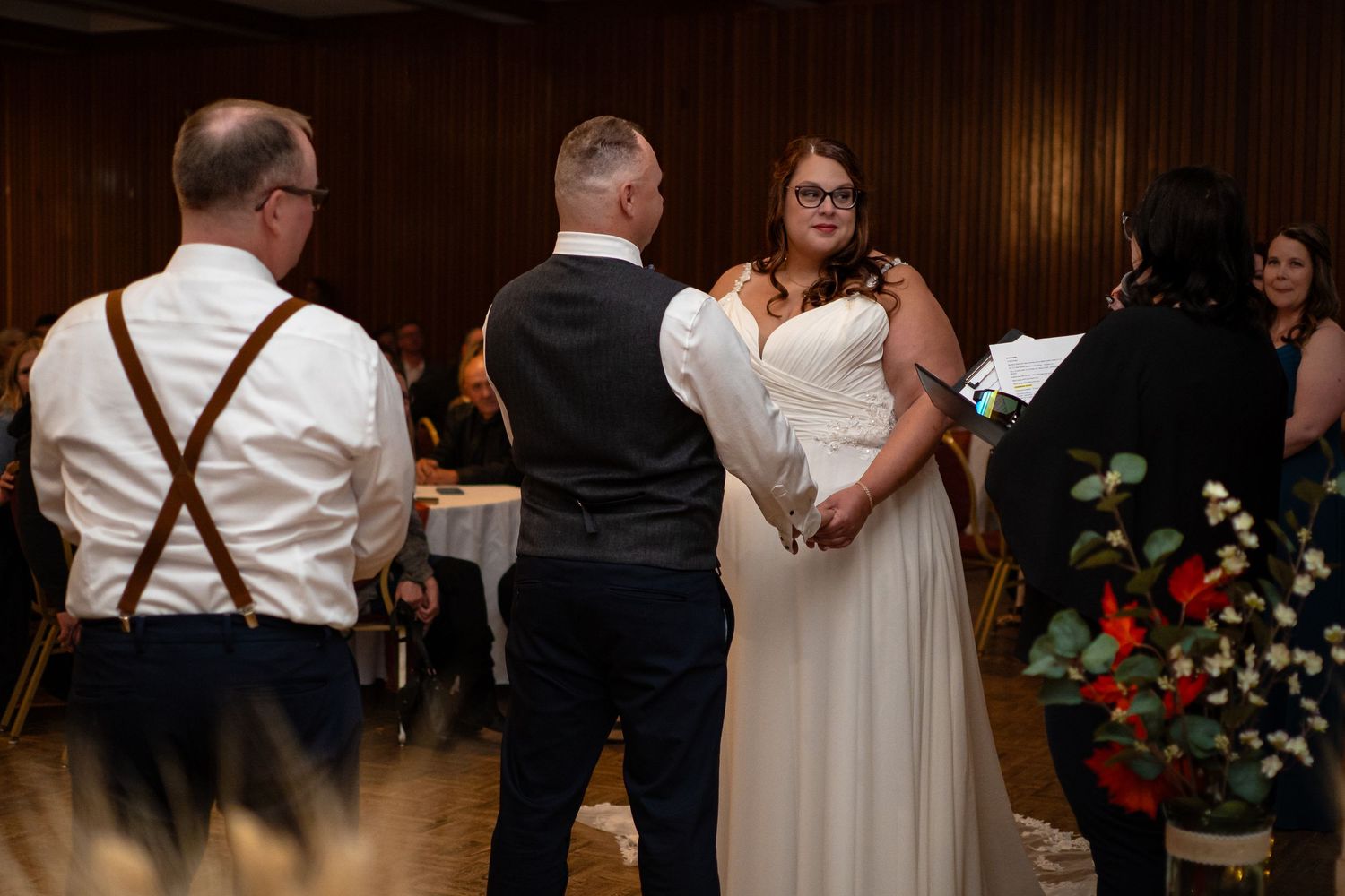 Wedding reception scene with formal attire and floral decorations.