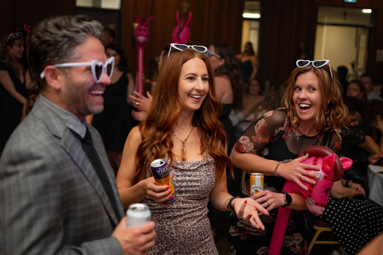 Guests dance and celebrate at an indoor wedding reception with festive lighting.