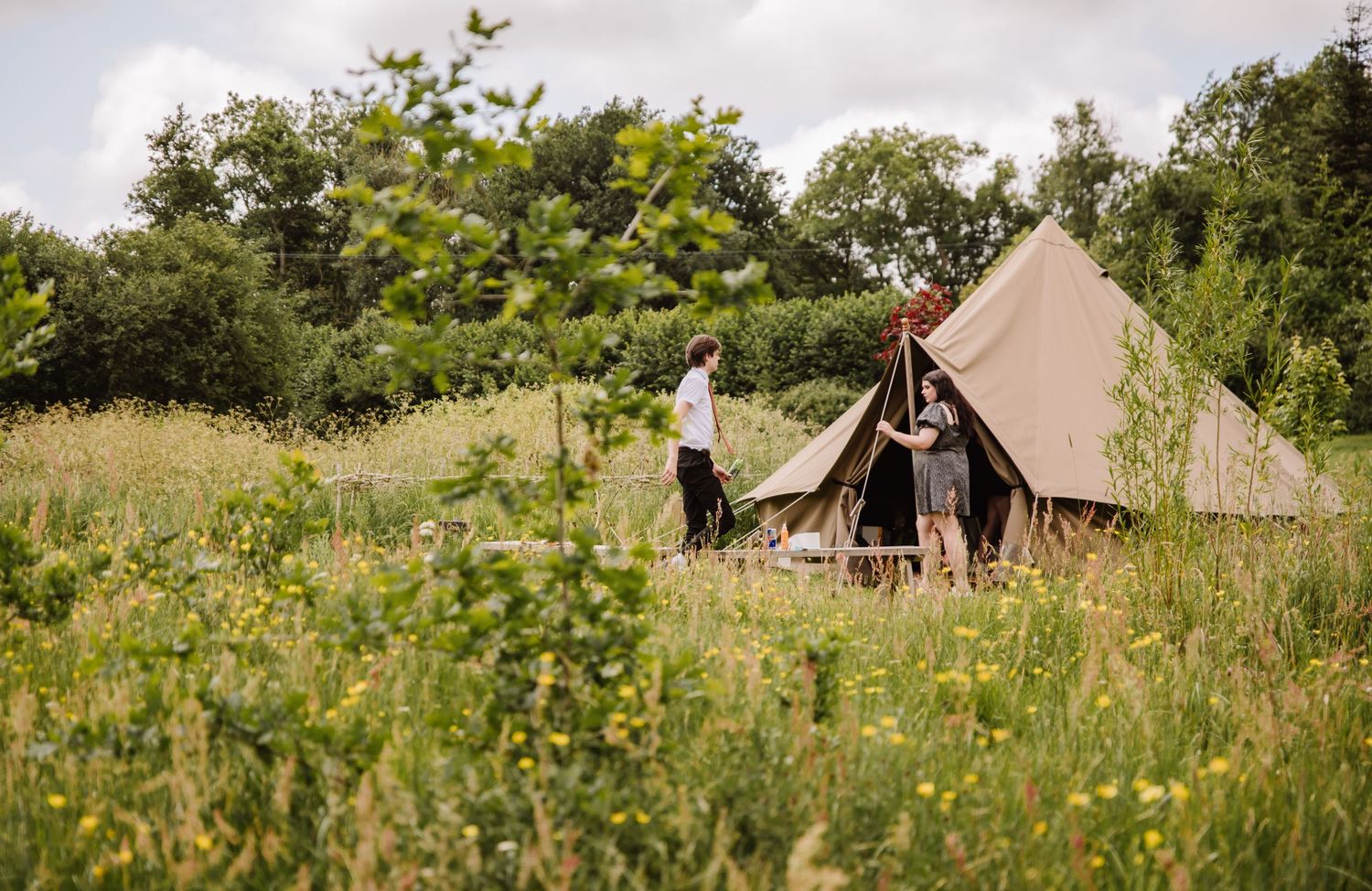 Rustic canvas bell tents set up in a wildflower meadow for luxury glamping experience and the Gaggle of Geese Wedding venue Dorchester