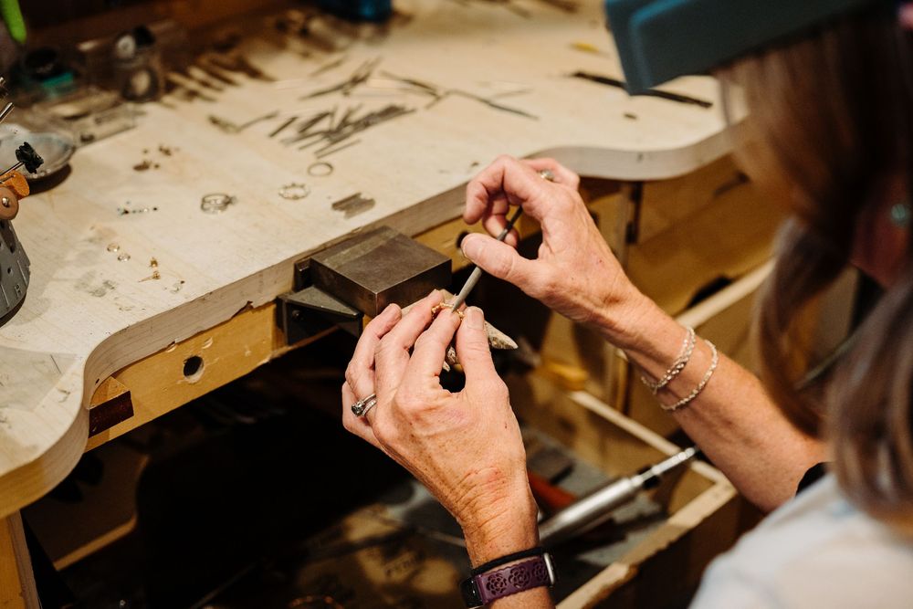 Close-up of hands carving intricate details into a wooden surface with specialized tools.