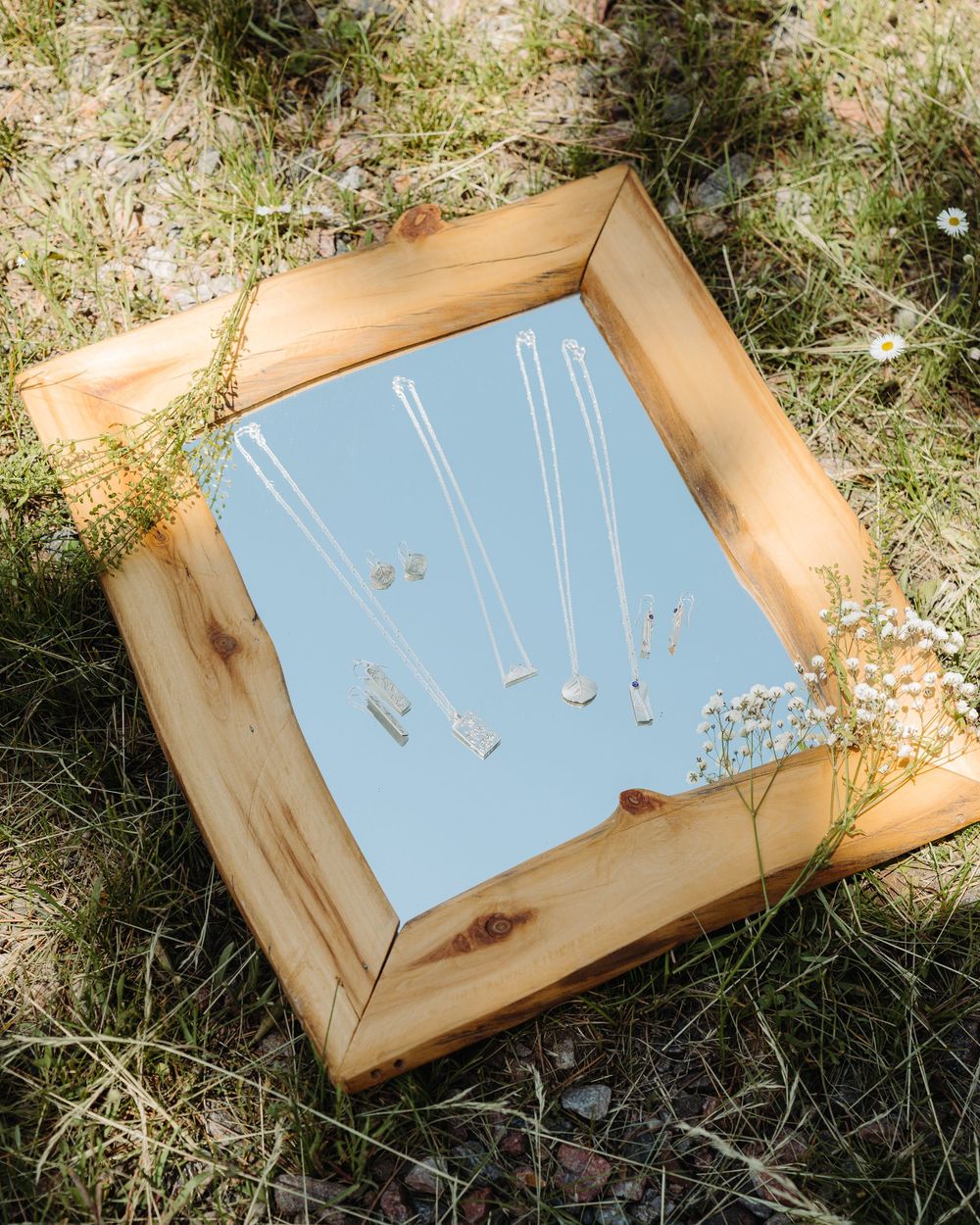A sequence of photos showing dangling necklaces arranged on a light blue background in a wooden frame.
