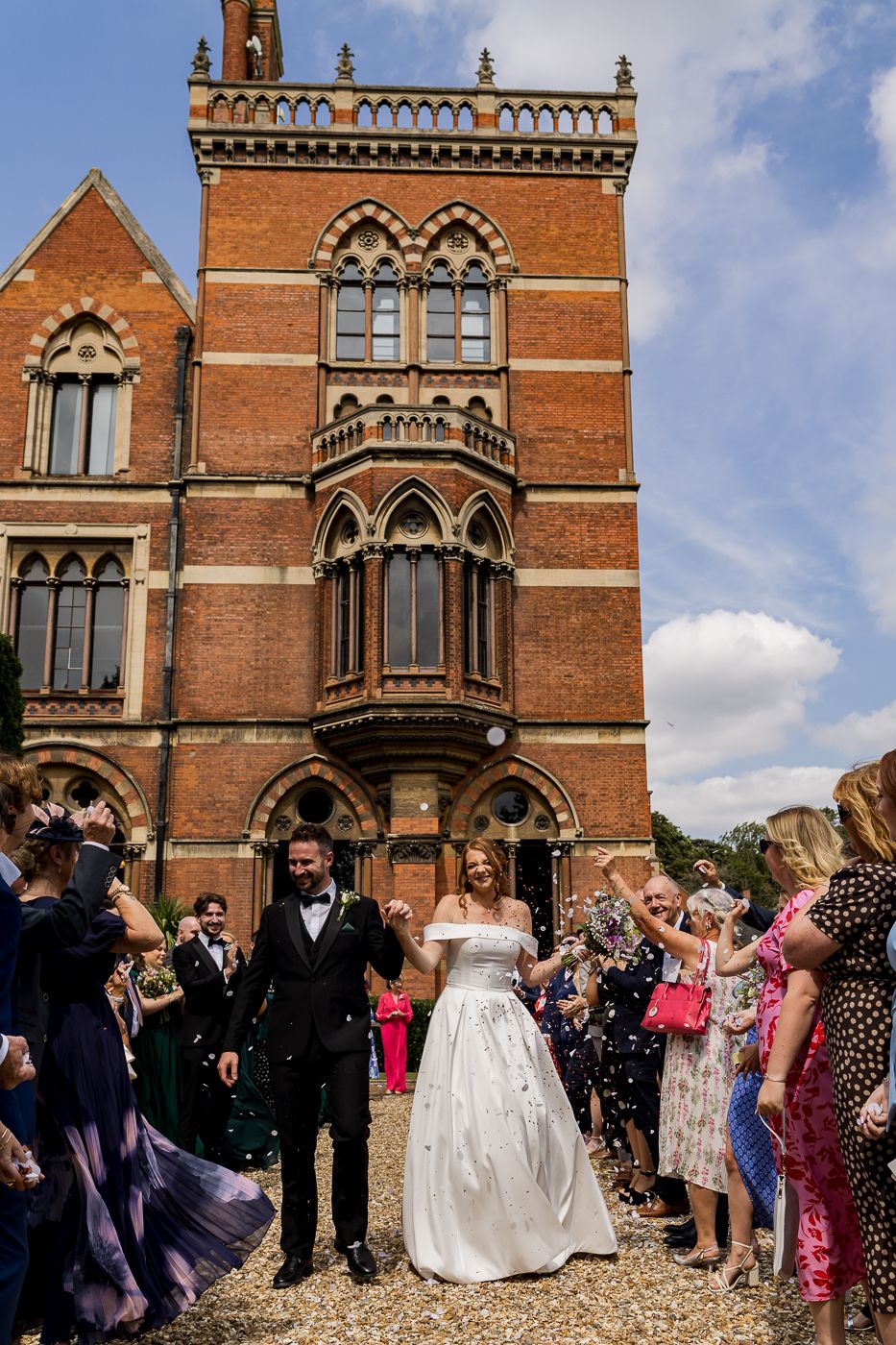 Wedding celebration outside Victorian Gothic building with ornate windows and architectural details.