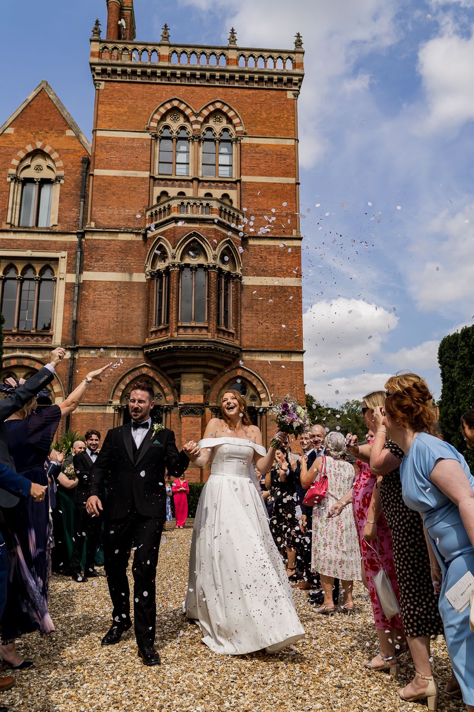 Joyful wedding celebration with confetti outside historic red brick building.