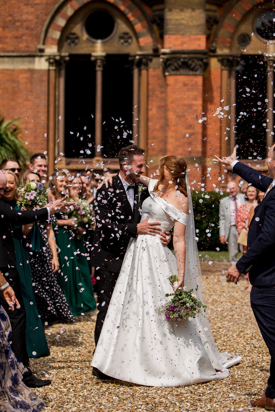 Wedding celebration with confetti shower against Gothic architectural backdrop.