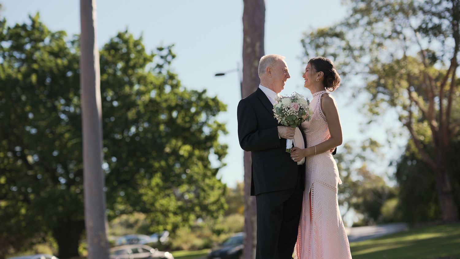 Wedding ceremony setup outdoors with white chairs and floral arrangements.
