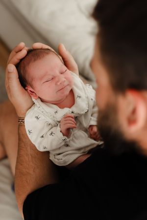 A series of intimate photos showing a baby being cradled and kissed while wearing a white patterned outfit.