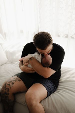 A tender moment between parent and child resting together on white bedding.
