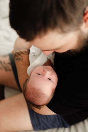 A tender parental moment captured in soft lighting with a baby in a white onesie.