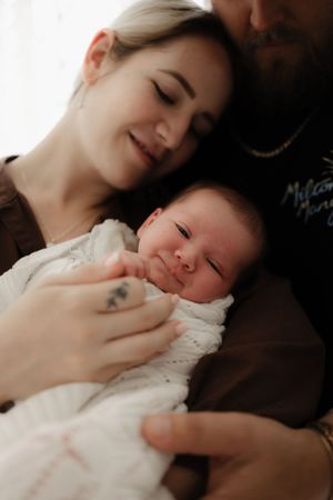 Baby sleeping peacefully in white clothing while being held close.
