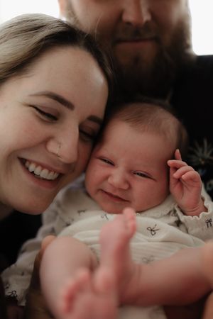 Joyful bonding moment with smiling parent and baby in white lace outfit.