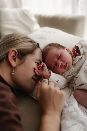 Intimate family moment showing parent and baby bonding on a brown couch.