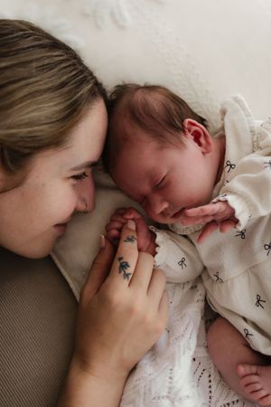A sequence of tender moments showing affectionate interactions with a sleeping baby in white clothing.