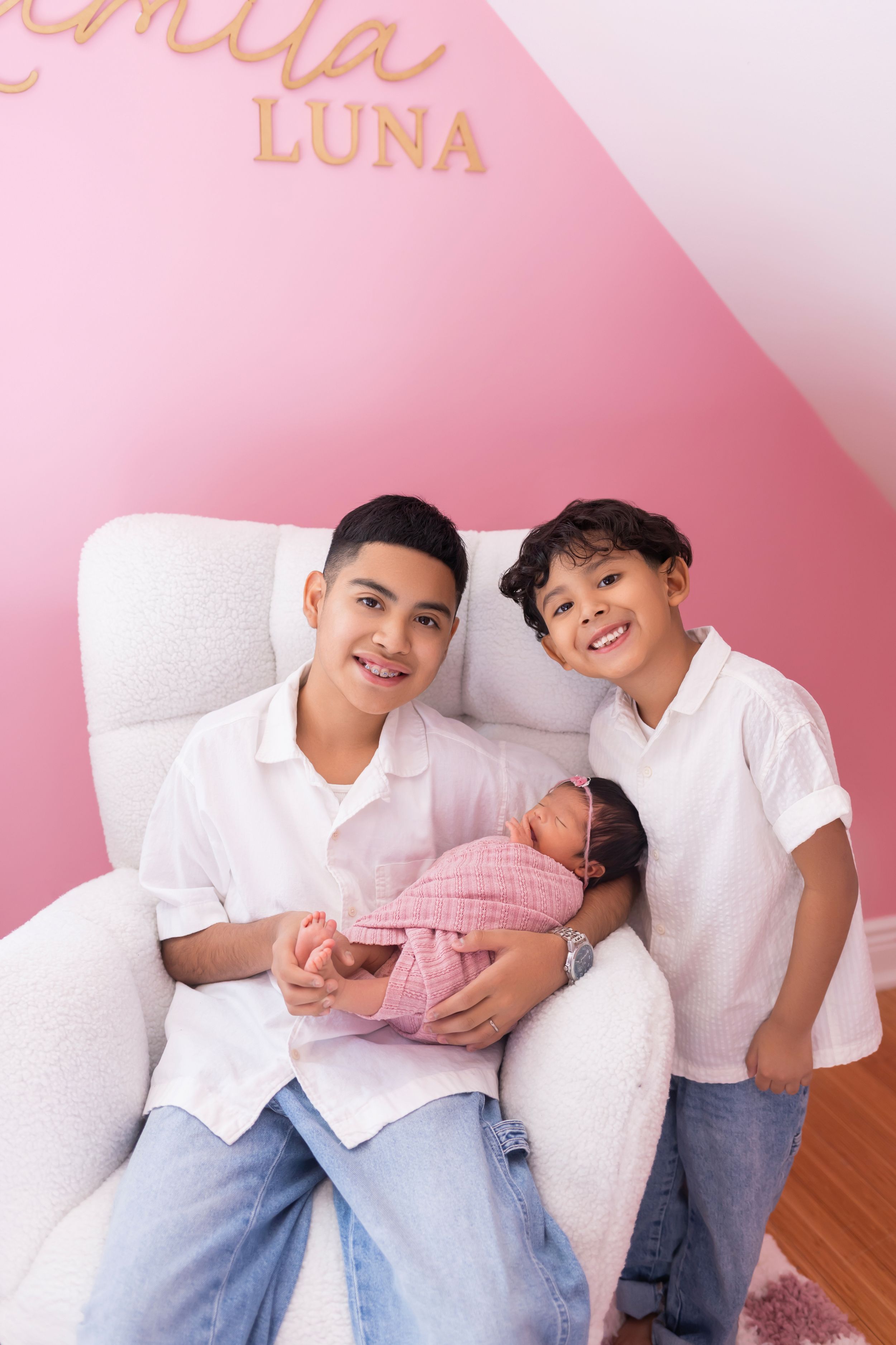 A series of four connected photos showing a family posing together against a pink wall background.